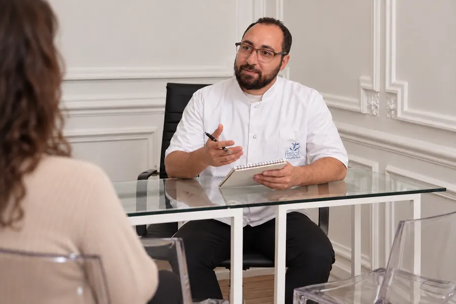 Hosam ASSAL prend des notes face à une patiente, au début de la séance