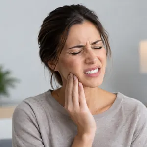 Femme qui grimace, la main sur la mâchoire